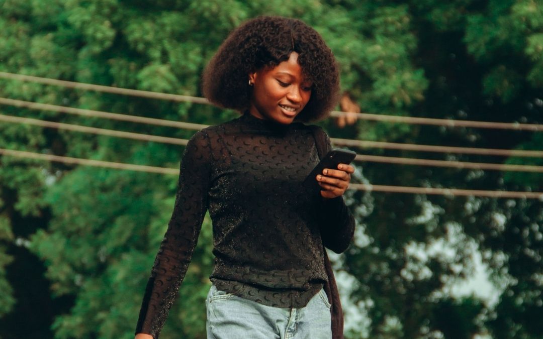 Woman looking at a smartphone outdoors while preparing to share a social media Story.