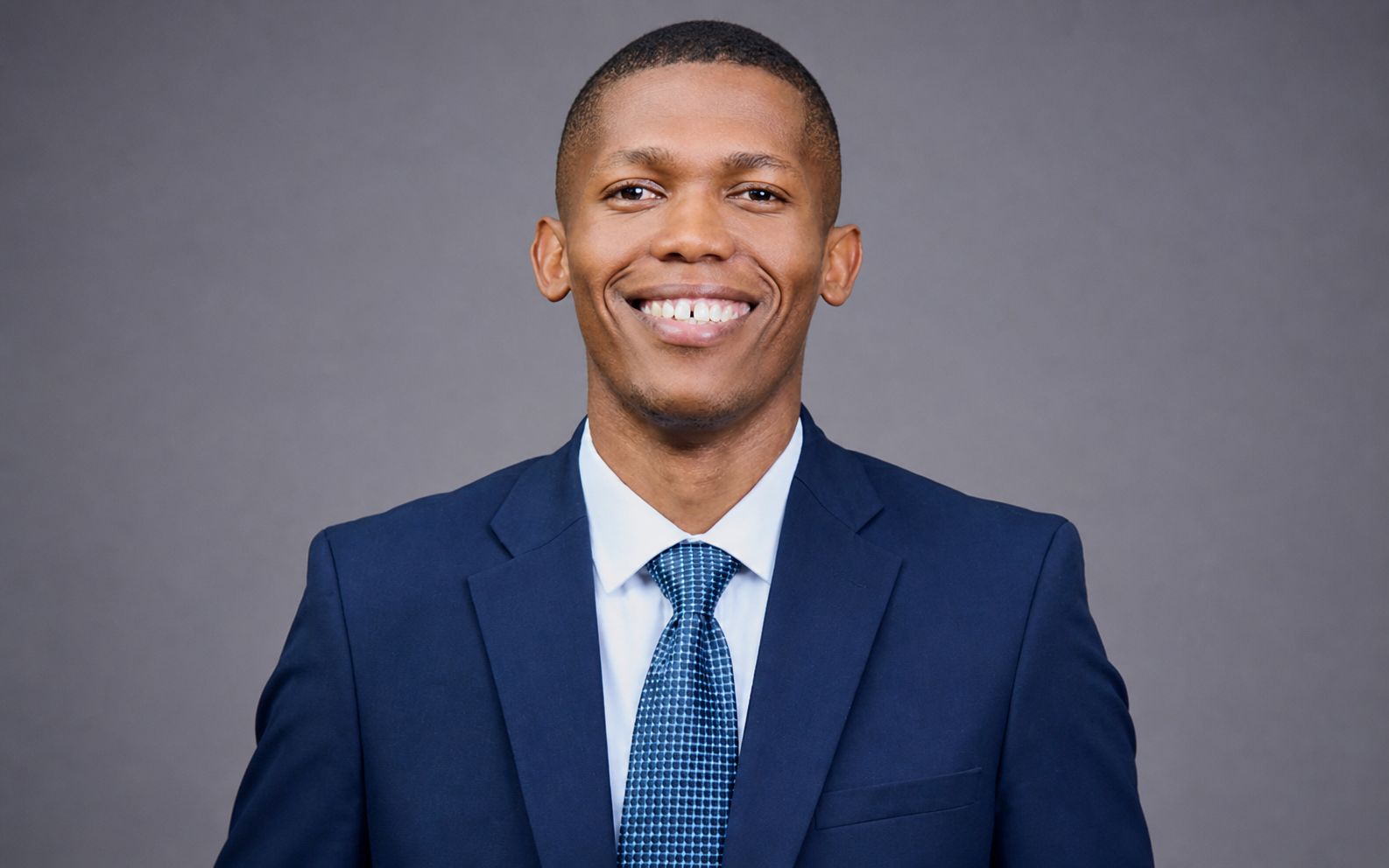 Matric learner Thabang Kgasane smiling in a suit during a student support campaign